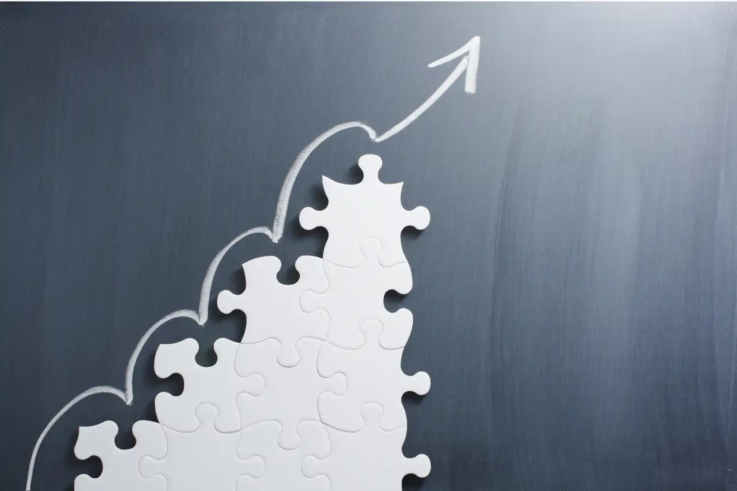 Man writing notes with a pencil and paper next to a laptop